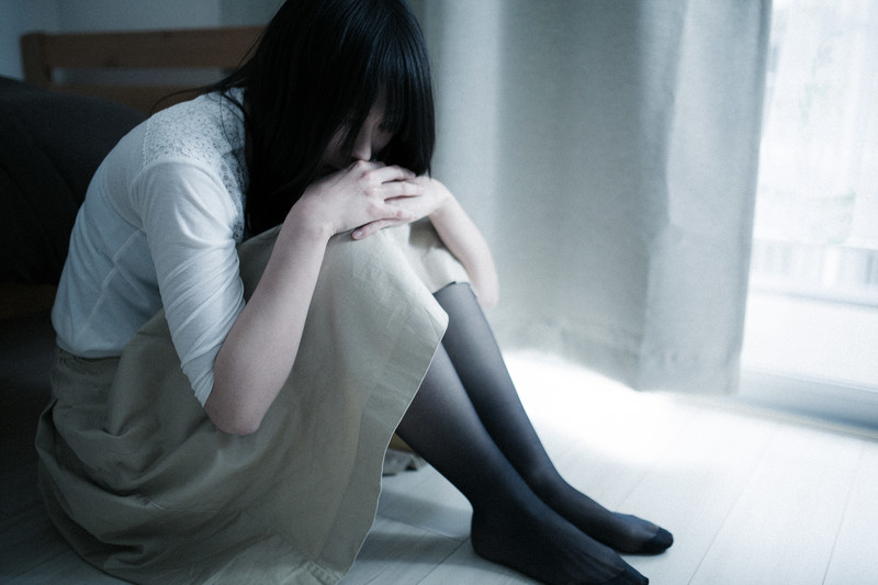 エネルギーが底をついたイメージを、膝を抱えてうずくまる女性の画像で表現