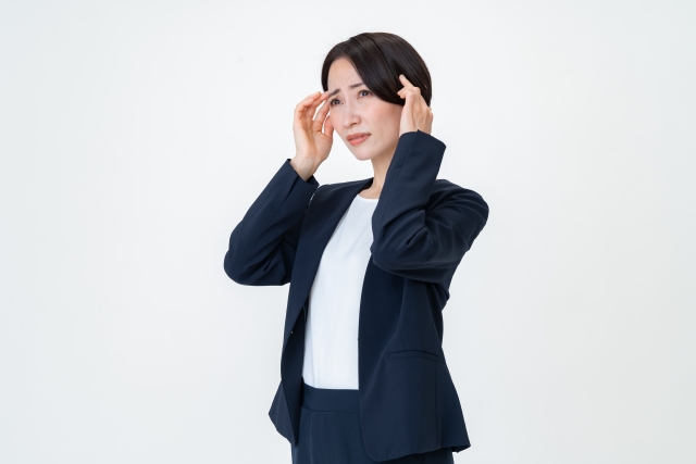 完璧主義のため、職場でいつも不安を抱えている女性のイメージを頭を抱えている女性の画像で表現