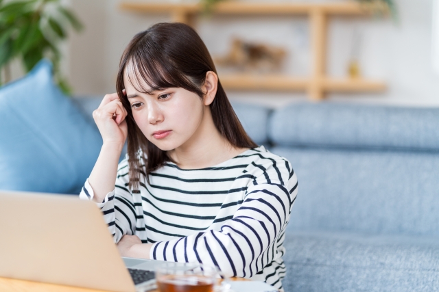 人と比べて落ち込むイメージを、パソコンの前で悩んでいる女性の画像で表現