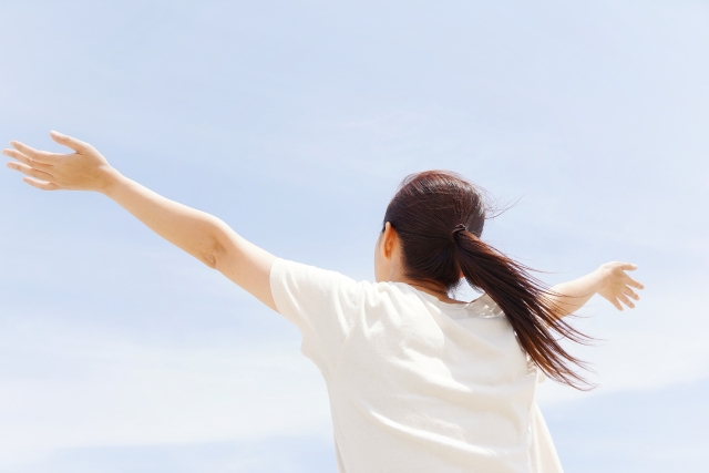 神経系に「もう大丈夫」と伝えているイメージを空に向かって深呼吸する女性の画像で表現