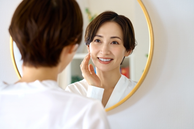 自分を労う声掛けのイメージを、鏡に向かってほほ笑む女性の画像で表現
