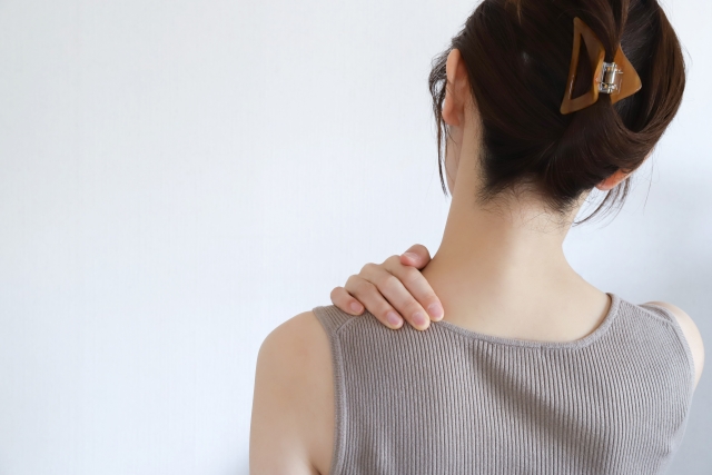 ストレスで筋肉がこわばったイメージを肩に手をのせる女性の画像で表現