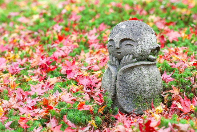 ありのままの自分を受け入れるイメージを、紅葉の中で微笑むお地蔵さんの画像で表現