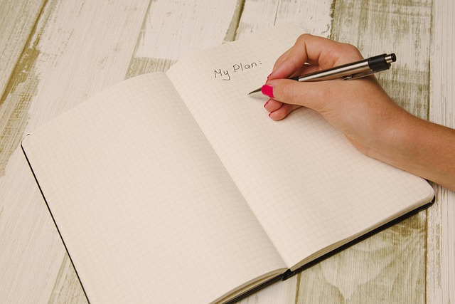 悩みを紙に書き出すイメージを、ノートにペンで文字を書いている女性の手の画像で表現